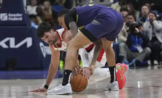 Portland Trail Blazers forward Deni Avdija, below, and New Orleans Pelicans guard Jordan Hawkins battle for a loose ball in the first half of an NBA basketball game in New Orleans, Wednesday, Jan. 8, 2025. (AP Photo/Gerald Herbert)