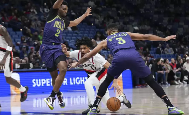 Portland Trail Blazers guard Shaedon Sharpe (17) drives to the basket between New Orleans Pelicans forward Herbert Jones (2) and guard CJ McCollum (3) in the first half of an NBA basketball game in New Orleans, Wednesday, Jan. 8, 2025. (AP Photo/Gerald Herbert)