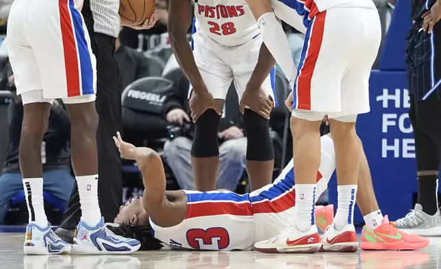 Teammates look over Detroit Pistons guard Jaden Ivey (23) after an incident during the second half of an NBA basketball game against the Orlando Magic, Wednesday, Jan. 1, 2025, in Detroit. (AP Photo/Carlos Osorio)