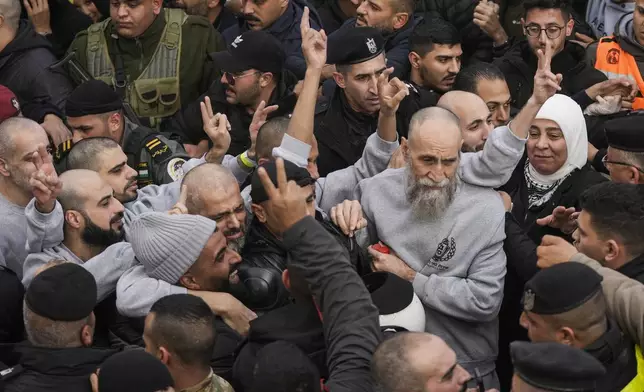 Palestinian Raed Al-Saadi, 57, right, and other prisoners are greeted by a crowd after being released from Israeli prison following a ceasefire agreement with Israel, in the West Bank city of Ramallah, Saturday, Jan. 25, 2025. (AP Photo/Mahmoud Illean)