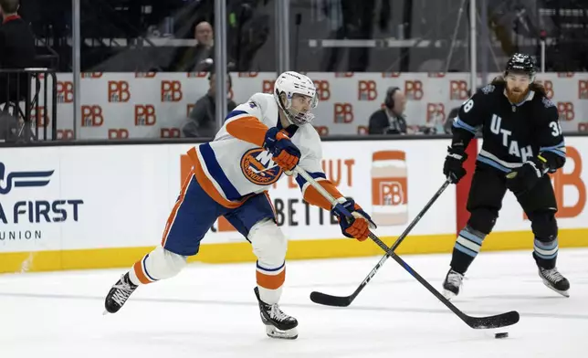 New York Islanders defenseman Adam Pelech, left, moves the puck against Utah Hockey Club center Liam O'Brien, right, during the first period of an NHL hockey game Saturday, Jan. 11, 2025, in Salt Lake City. (AP Photo/Melissa Majchrzak)