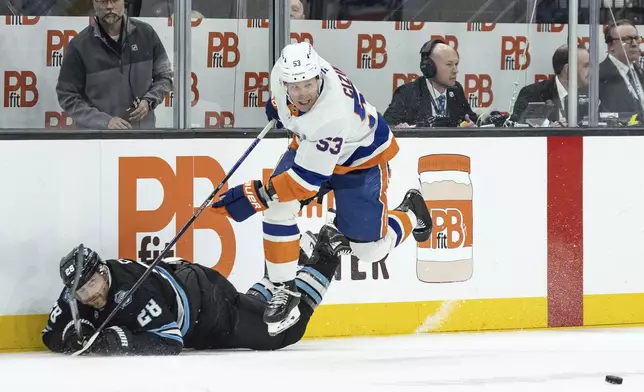 Utah Hockey Club defenseman Ian Cole (28) goes down fighting for the puck against New York Islanders center Casey Cizikas (53) during the second period of an NHL hockey game Saturday, Jan. 11, 2025, in Salt Lake City. (AP Photo/Melissa Majchrzak)