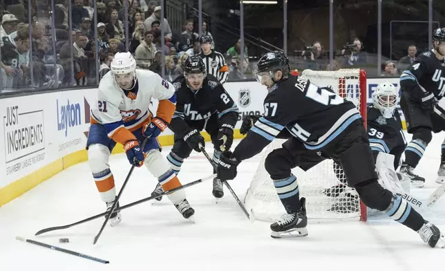 New York Islanders center Kyle Palmieri (21) fights for the puck against Utah Hockey Club center Barrett Hayton (27) and defenseman Nick DeSimone (57) during the second period of an NHL hockey game Saturday, Jan. 11, 2025, in Salt Lake City. (AP Photo/Melissa Majchrzak)