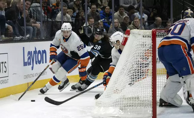 New York Islanders defenseman Dennis Cholowski (25) moves the puck against Utah Hockey Club center Liam O'Brien (38) during the first period of an NHL hockey game Saturday, Jan. 11, 2025, in Salt Lake City. (AP Photo/Melissa Majchrzak)