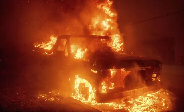 The Eaton Fire burns a vehicle Wednesday, Jan. 8, 2025 in Altadena, Calif. (AP Photo/Ethan Swope)