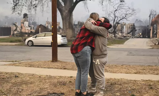 Lisa Diaz hugs a neighbor outside of their homes as the Eaton Fire sweeps through the area Wednesday, Jan. 8, 2025, in Altadena, Calif. (AP Photo/Nic Coury)