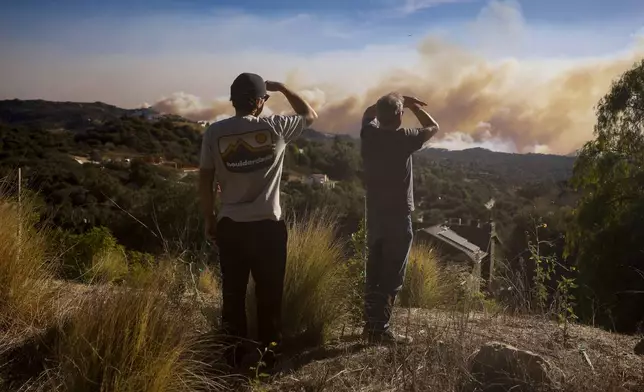 Topanga Canyon inhabitants look on as the Palisades Fire burns in the hills between Pacific Palisades and Malibu Wednesday, Jan. 8, 2025 in Topanga, Calif. (AP Photo/Etienne Laurent)