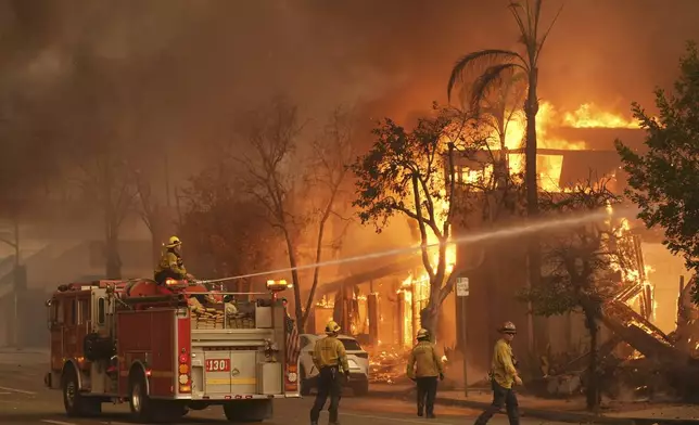 Firefighters hose down a burning structure on Lake Avenue, Wednesday, Jan. 8, 2025, in the downtown Altadena section of Pasadena, Calif. (AP Photo/Chris Pizzello)