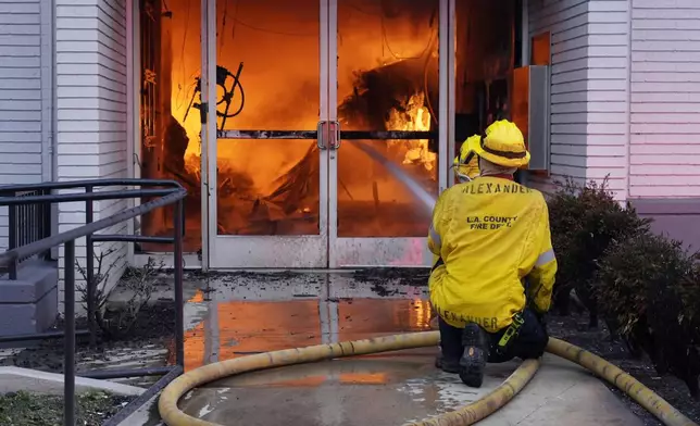 Firefighters aim a hose at the entrance to a Bank of America engulfed in flames on Lake Avenue, Wednesday, Jan. 8, 2025, in the Altadena section of Pasadena, Calif. (AP Photo/Chris Pizzello)