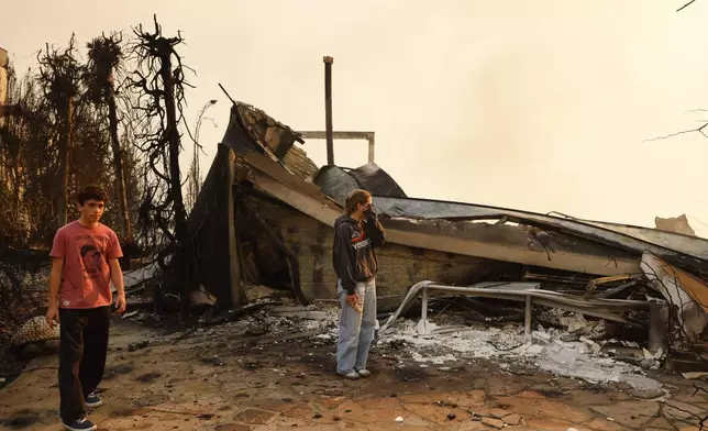 Fallon Prockiw-Kline, center, gets emotional in front of her home which was damaged by the Palisades Fire, Wednesday, Jan. 8, 2025, in Malibu, Calif. (AP Photo/Etienne Laurent)