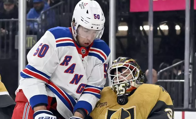 Vegas Golden Knights goaltender Ilya Samsonov, right, blocks the puck against New York Rangers left wing Will Cuylle (50) during the first period of an NHL hockey game Saturday, Jan. 11, 2025, in Las Vegas. (AP Photo/David Becker)