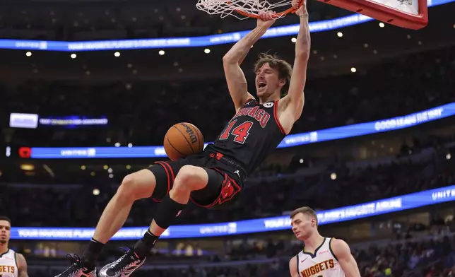 Chicago Bulls forward Matas Buzelis (14) hangs from the rim after slam-dunking during the first half of an NBA basketball game against the Denver Nuggets, Monday, Jan. 27, 2025, in Chicago. (AP Photo/Melissa Tamez)