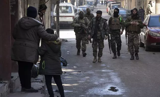 People stand outside their homes as members of the new security forces take part in an operation to detain, according to the state media, militiamen affiliated with ousted president Bashar Assad, at a residential area, in Homs, Syria, Thursday, Jan. 2, 2025. (AP Photo/Leo Correa)