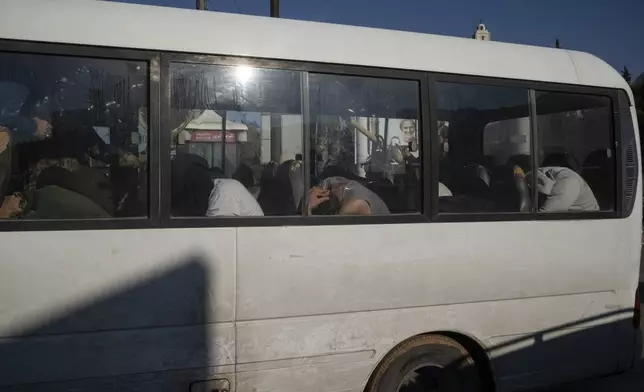 Detained men, suspected of being part of militias of the ousted president Bashar Assad, are driven in a bus as members of the new security forces take part in an operation to detain them on a residential area in Homs, Syria, Thursday, Jan. 2, 2025. (AP Photo/Leo Correa)