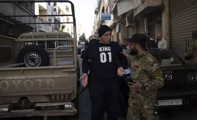 A member of the new security forces detains a man suspected of being part of militias of the ousted president Bashar Assad, during an operation at a residential area in Homs, Syria, Thursday, Jan. 2, 2025. (AP Photo/Leo Correa)