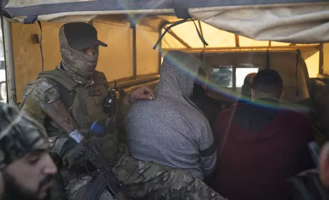 Members of the new security forces detain men suspected of being part of militias of the ousted president Bashar Assad, during an operation on a residential area in Homs, Syria, Thursday, Jan. 2, 2025. (AP Photo/Leo Correa)