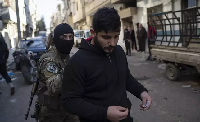 A member of the new security forces detains a man suspected of being part of militias of the ousted president Bashar Assad, during an operation at a residential area in Homs, Syria, Thursday, Jan. 2, 2025. (AP Photo/Leo Correa)