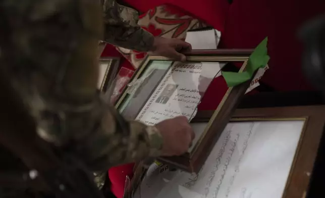 A member of the new security forces destroys a diploma with an image depicting the late Syrian President Hafez Assad during an operation to detain, according to the state media, militiamen affiliated with ousted president Bashar Assad, at a residential area, in Homs, Syria, Thursday, Jan. 2, 2025. (AP Photo/Leo Correa)