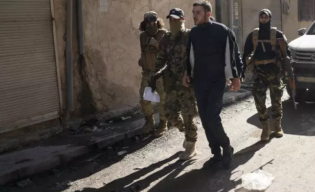 Members of the security forces of the newly formed Syrian government detain a man suspected of being part of militias of the ousted president Bashar Assad, during an operation on a residential area in Homs, Syria, Thursday, Jan. 2, 2025. (AP Photo/Leo Correa)