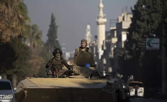 Members of the new security forces move on the top of a tank during an operation to detain, according to the state media, militiamen affiliated with ousted president Bashar Assad, in Homs, Syria, Thursday, Jan. 2, 2025. (AP Photo/Leo Correa)