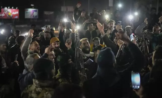 Young men cheer as members of the new security forces, primarily fighters from Hayat Tahrir al-Sham (HTS), fire into the air in celebration after spending most of the day searching for militiamen loyal to ousted President Bashar Assad who refused to surrender their weapons to the new authorities in Homs, Syria, Thursday, Jan. 2, 2025. (AP Photo/Leo Correa)