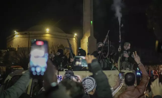 Young men cheer as members of the new security forces, primarily fighters from Hayat Tahrir al-Sham (HTS), fire into the air in celebration after spending most of the day searching for militiamen loyal to ousted President Bashar Assad who refused to surrender their weapons to the new authorities in Homs, Syria, Thursday, Jan. 2, 2025. (AP Photo/Leo Correa)