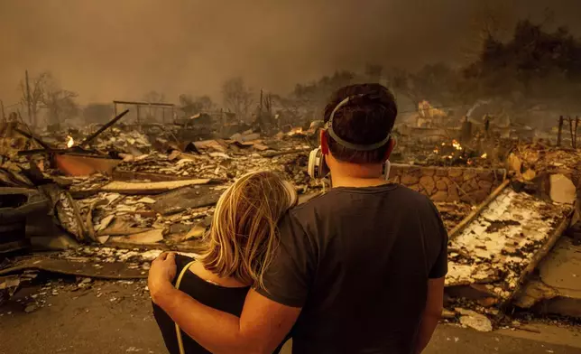 Megan Mantia, left, and her boyfriend Thomas, return to Mantia's fire-damaged home after the Eaton Fire swept through, Wednesday, Jan. 8, 2025, in Altadena, Calif. (AP Photo/Ethan Swope)