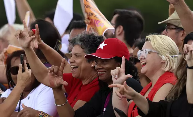 Social movement activists make the "L" for Lula during a pro-democracy event on the second anniversary of the alleged coup attempt when supporters of former President Jair Bolsonaro invaded government buildings and called for military intervention in Brasilia, Brazil, Wednesday, Jan. 8, 2025. (AP Photo/Luis Nova)