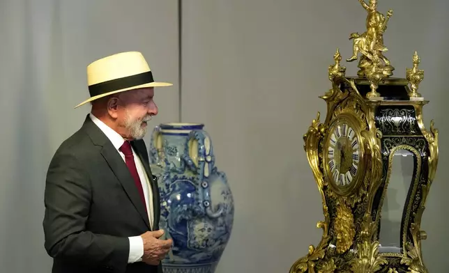 Brazilian President Luiz Inacio Lula da Silva looks at the Historic Clock received as a gift from the Swiss State that was restored after being destroyed during an attack on the presidential palace, during a ceremony marking two years since the alleged coup attempt when supporters of former President Jair Bolsonaro invaded government buildings and called for military intervention, in Brasilia, Brazil, Wednesday, Jan. 8, 2025. (AP Photo/Eraldo Peres)