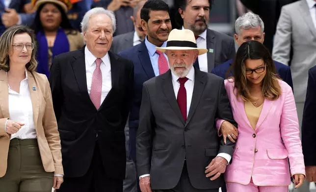 Brazilian President Luiz Inacio Lula da Silva, with a hat, and his wife Rosangela da Silva, descend the ramp of the presidential palace during a ceremony marking two years since the alleged coup attempt when supporters of former President Jair Bolsonaro invaded government buildings and called for military intervention in Brasilia, Brazil, Wednesday, Jan. 8, 2025. (AP Photo/Eraldo Peres)