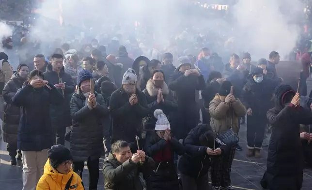 People holding incense sticks pray on the first day of the Chinese Lunar New Year at Lama Temple in Beijing on Wednesday, Jan. 29, 2025. (AP Photo/Aaron Favila)