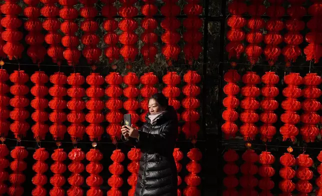 A woman takes photos as she visits the Ditan Temple Fair on the first day of the Chinese Lunar New Year in Beijing on Wednesday, Jan. 29, 2025. (AP Photo/Aaron Favila)