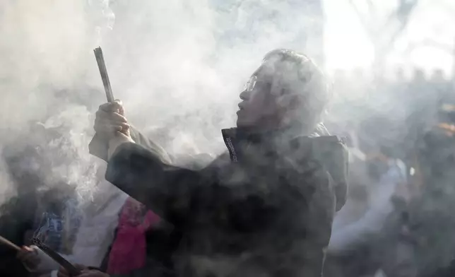 A man holding incense sticks prays on the first day of the Chinese Lunar New Year at Lama Temple in Beijing on Wednesday, Jan. 29, 2025. (AP Photo/Aaron Favila)