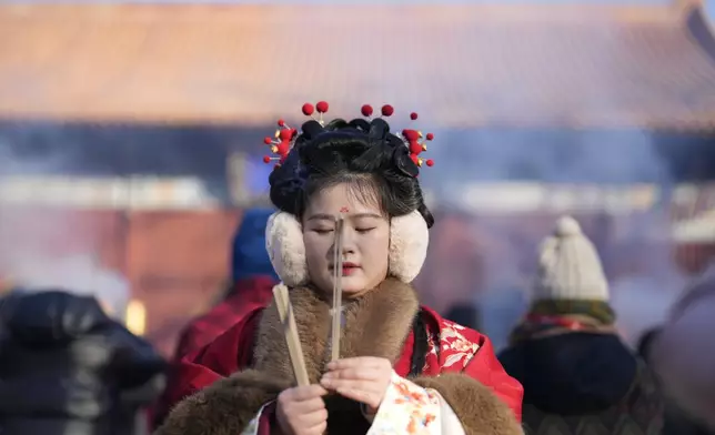 A woman in a traditional costume prays on the first day of the Chinese Lunar New Year at Lama Temple in Beijing on Wednesday, Jan. 29, 2025. (AP Photo/Aaron Favila)