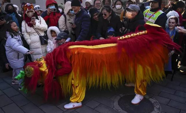 People touch during a lion dance performance at the Dongyue Temple on the first day of the Chinese Lunar New Year in Beijing on Wednesday, Jan. 29, 2025. (AP Photo/Andy Wong)