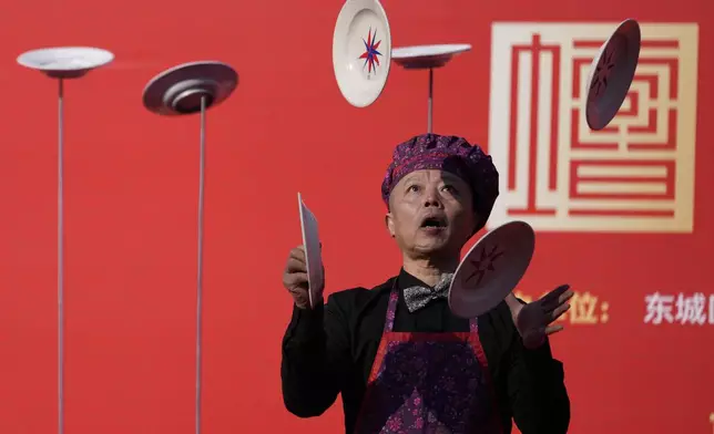 A performer juggles plates during a presentation at the crowded Ditan Temple Fair on the first day of the Chinese Lunar New Year in Beijing on Wednesday, Jan. 29, 2025. (AP Photo/Aaron Favila)