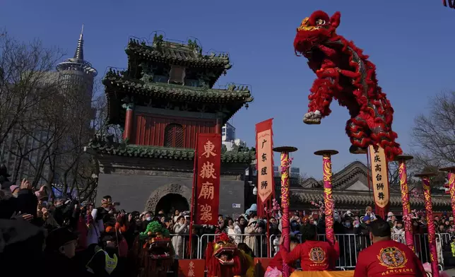 People watch as an artist performs an acrobatic lion dance at the Dongyue Temple on the first day of the Chinese Lunar New Year in Beijing on Wednesday, Jan. 29, 2025. (AP Photo/Andy Wong)