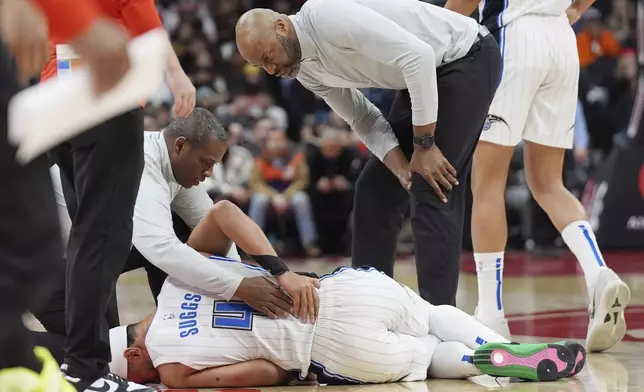 Orlando Magic head coach Jamahl Mosley, right attends to guard Jalen Suggs (4) after he suffered an injury during the first half of an NBA basketball game against the Toronto Raptors, Friday, Jan. 3, 2025 in Toronto. (Frank Gunn/The Canadian Press via AP)