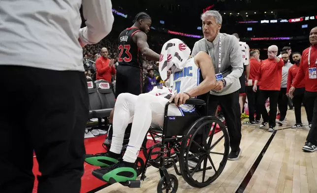 Orlando Magic guard Jalen Suggs (4) leaves the game in a wheelchair after suffering an injury during the first half of an NBA basketball game against the Toronto Raptors in Toronto, Friday, Jan. 3, 2025. (Frank Gunn/The Canadian Press via AP)