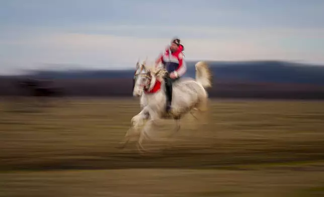 A man takes part in a traditional horse race during Epiphany celebrations in the village of Pietrosani, Romania, Monday, Jan. 6, 2025. (AP Photo/Andreea Alexandru)