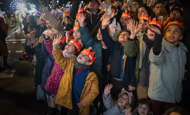 Children greet one of the three wise men as they attend the traditional "Cabalgata de Reyes" parade in Barcelona, Spain, Sunday, Jan. 5, 2025, as part of the festivities marking the Catholic feast of Epiphany. (AP Photo/Emilio Morenatti)