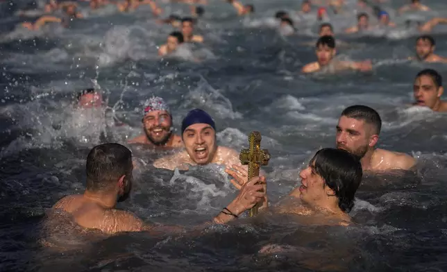 Greek Orthodox faithful hold up a wooden crucifix after being retrieved in the Golden Horn during the Epiphany ceremony in Istanbul, Turkey, Monday, Jan. 6, 2025. (AP Photo/Khalil Hamra)