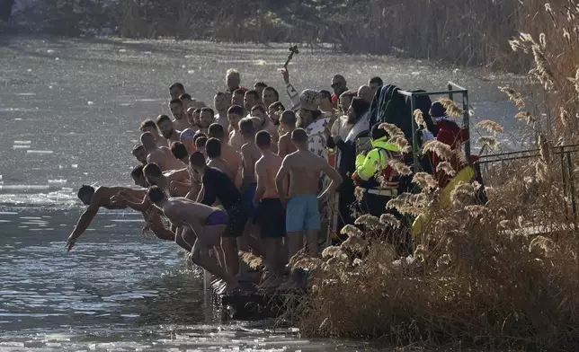 Bulgarian Patriarch Danail throws a wooden cross in the icy lake as believers jump to retrieve it, in Sofia, Monday, Jan. 6, 2025. (AP Photo/Valentina Petrova)