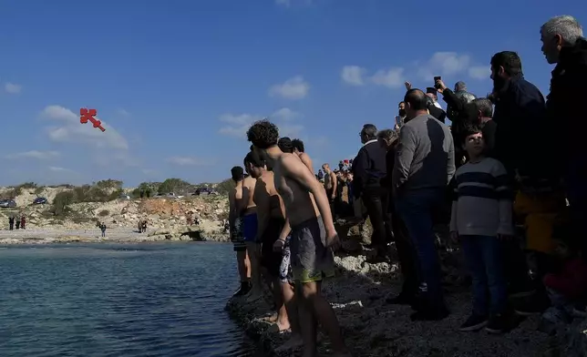 A Christian orthodox priest throws the cross as the pilgrim swimmers prepare to dive into the sea waters, during an epiphany ceremony to bless the sea, on the southeast village of Xylophagou, Cyprus, Monday, Jan. 6, 2025. (AP Photo/Petros Karadjias)