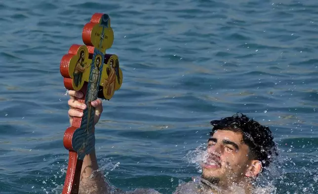 A pilgrim holds the cross after it was thrown by an Orthodox priest into the water, during an epiphany ceremony to bless the sea, on the southeast village of Xylophagou, Cyprus, Monday, Jan. 6, 2025. (AP Photo/Petros Karadjias)