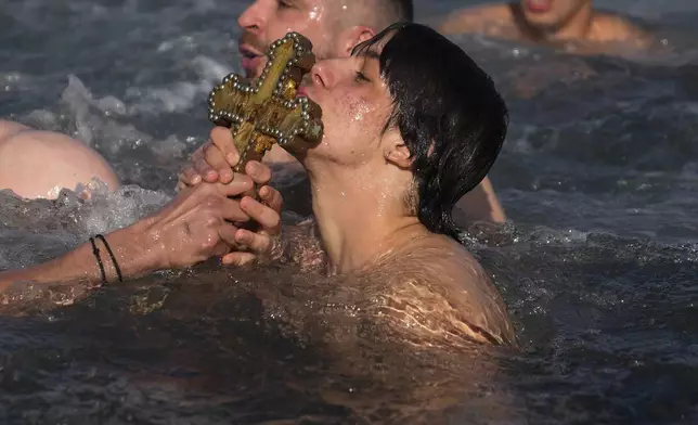 A Greek Orthodox faithful kisses a wooden crucifix after being retrieved in the Golden Horn during the Epiphany ceremony in Istanbul, Turkey, Monday, Jan. 6, 2025. (AP Photo/Khalil Hamra)