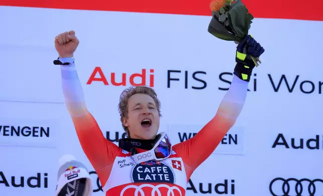 Switzerland's Marco Odermatt celebrates on the podium after winning an alpine ski, men's World Cup downhill, in Wengen, Switzerland, Saturday, Jan. 18, 2025. (AP Photo/Giovanni Maria Pizzato)