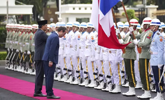 France's Defense Minister Sebastien Lecornu, right, and Indonesian Defense Minister Sjafrie Sjamsoeddin salute the national flags as they inspect honor guards during the welcoming ceremony prior to their meeting in Jakarta, Indonesia, Friday, Jan. 31, 2025. (AP Photo/Tatan Syuflana)