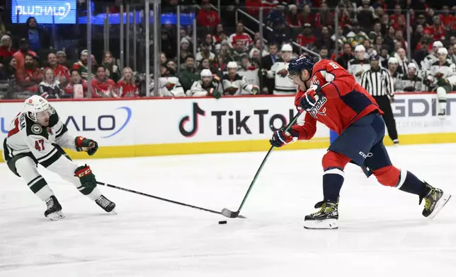 Washington Capitals left wing Alex Ovechkin (8) shoots the puck as Minnesota Wild defenseman Declan Chisholm (47) defends during the first period of an NHL hockey game, Thursday, Jan. 2, 2025, in Washington. (AP Photo/Nick Wass)