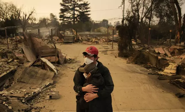 Ari Rivera, rear, Anderson Hao hold each other in front of their destroyed home in Altadena, Calif., Thursday, Jan. 9, 2025. (AP Photo/John Locher)
